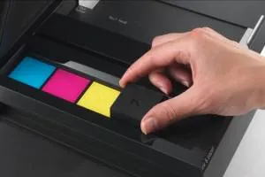 Hand inserting cyan, magenta, yellow and black toner into a copier